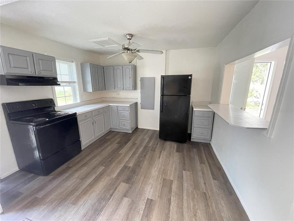A kitchen features gray cabinets, black appliances, and wood-look flooring — 1022 OREGON AVENUE, ST CLOUD, FL