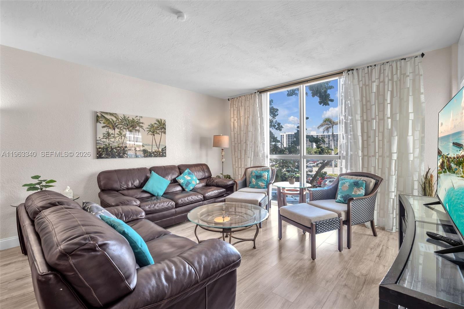 A living room features brown leather sofas, a glass coffee table, and large windows — 3801 S Ocean Dr # 2W, Hollywood FL 33019, HOLLYWOOD, FL