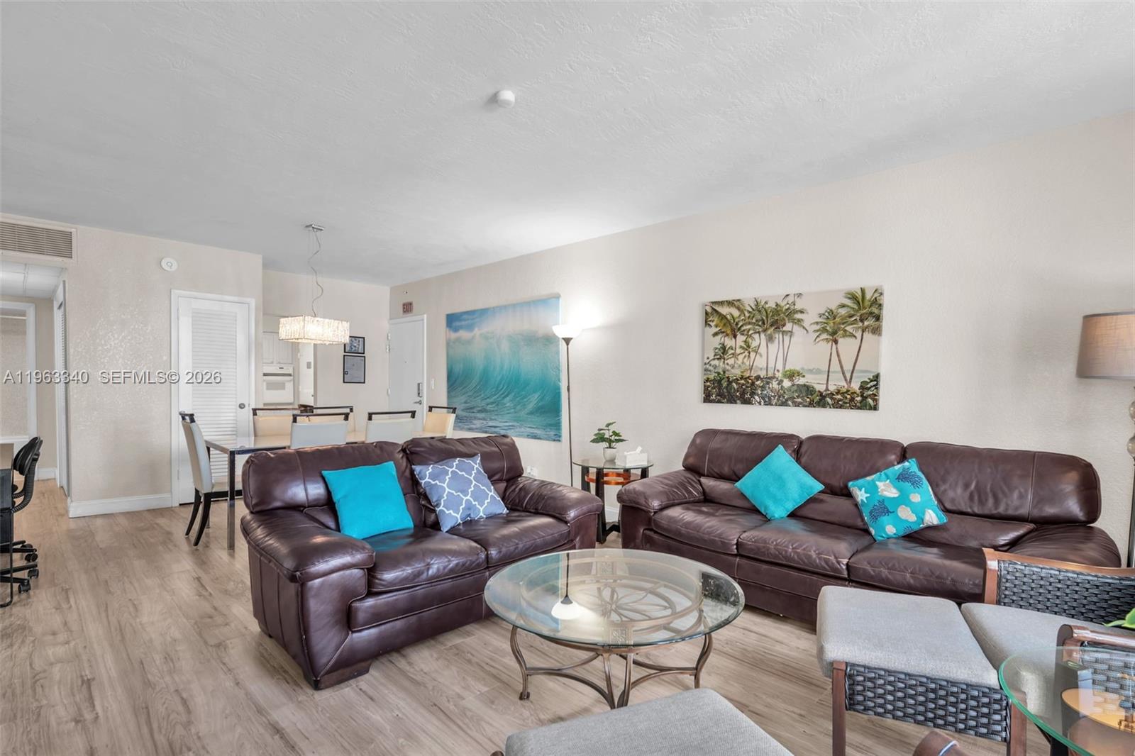 A living room features two brown leather sofas, a glass coffee table, and coastal artwork — 3801 S Ocean Dr # 2W, Hollywood FL 33019, HOLLYWOOD, FL
