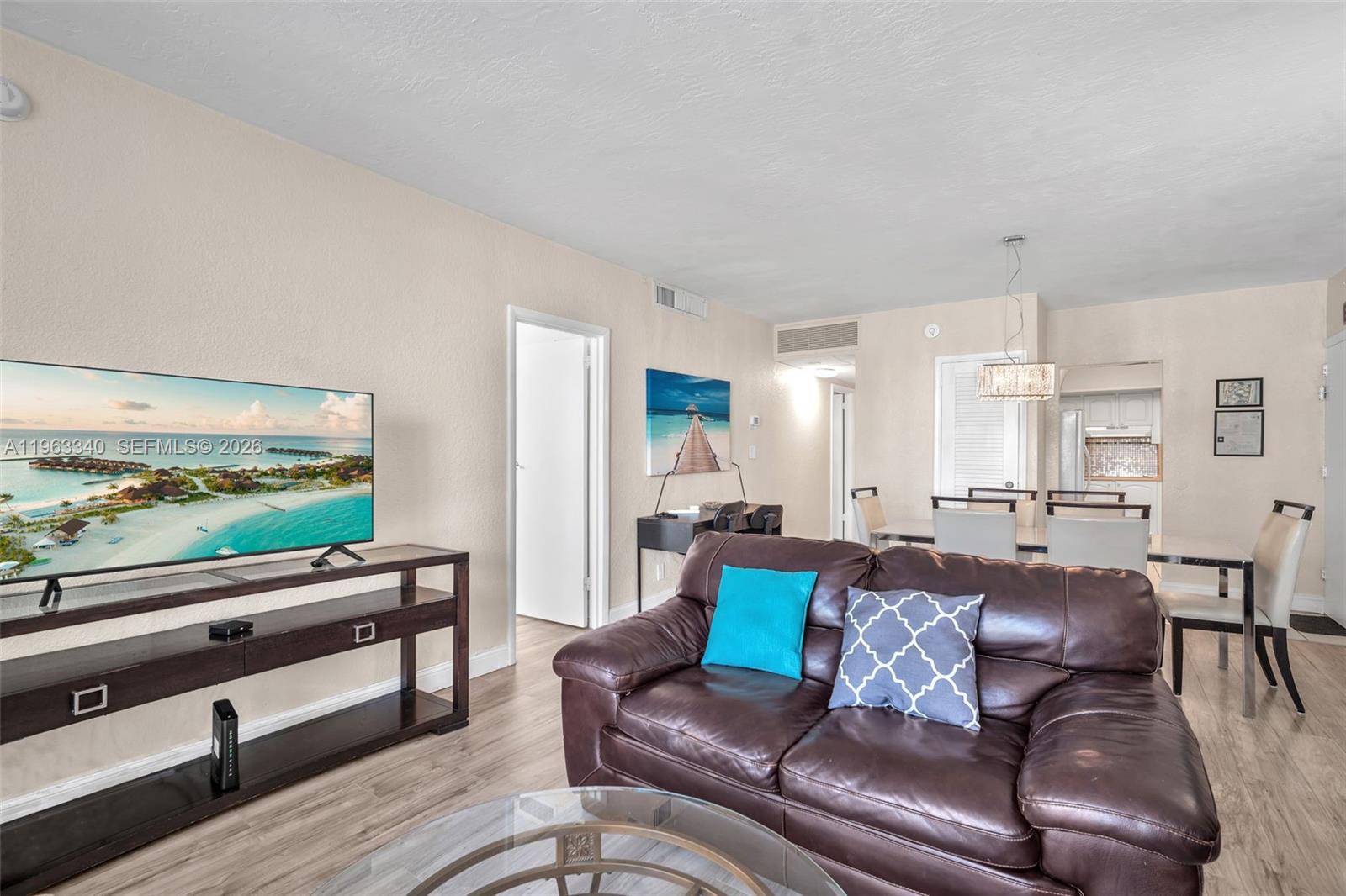 A living room features a brown leather sofa, a television on a stand, and dining area — 3801 S Ocean Dr # 2W, Hollywood FL 33019, HOLLYWOOD, FL