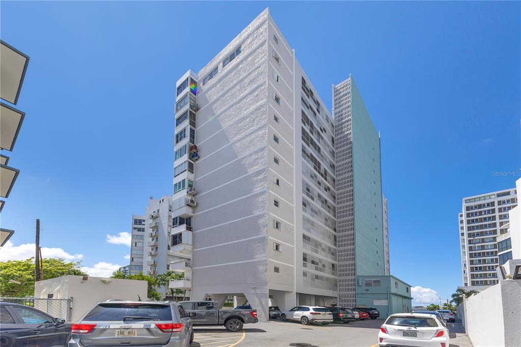 A view of a tall, multi-story apartment building with a parking lot in front — 14 CALLE MARSEILLES, SAN JUAN, PR