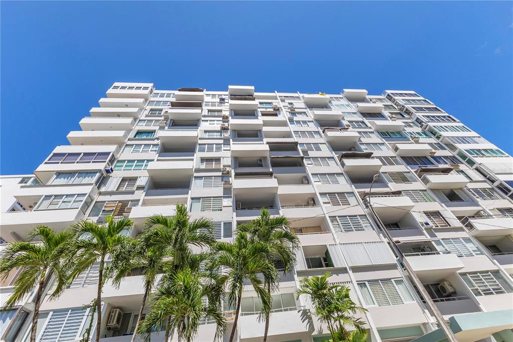 A low-angle view of a white multi-story apartment building with balconies and palm trees — 14 CALLE MARSEILLES, SAN JUAN, PR