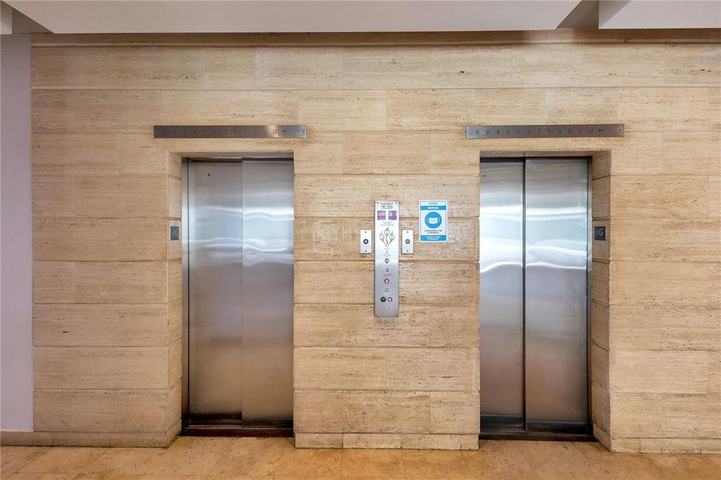 Two stainless steel elevator doors are set into a beige stone-tiled wall — 14 CALLE MARSEILLES, SAN JUAN, PR