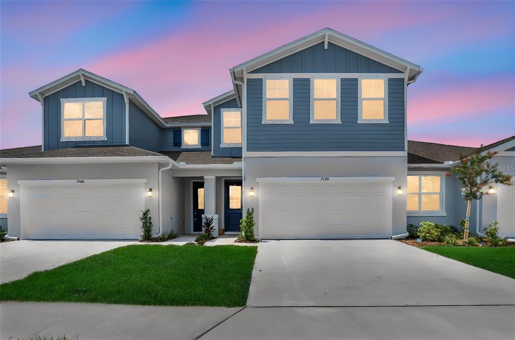 A two-story house with blue siding, two garage doors, and a concrete driveway at dusk — 7570 SEA OAK COURT, PARRISH, FL