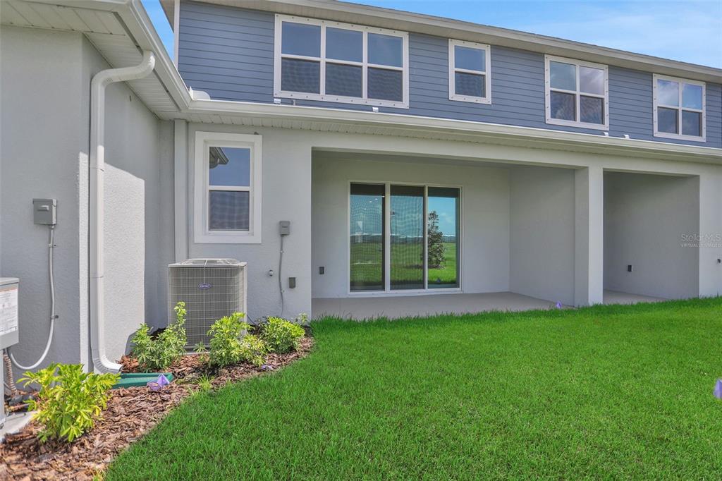 The exterior view shows a house with a covered patio, sliding glass doors, and lawn — 7570 SEA OAK COURT, PARRISH, FL