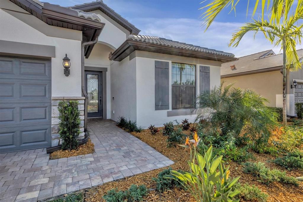 A single-story house exterior features a gray garage, stone accents, and a paved walkway — 5721 SWEET LEAF WAY, SARASOTA, FL