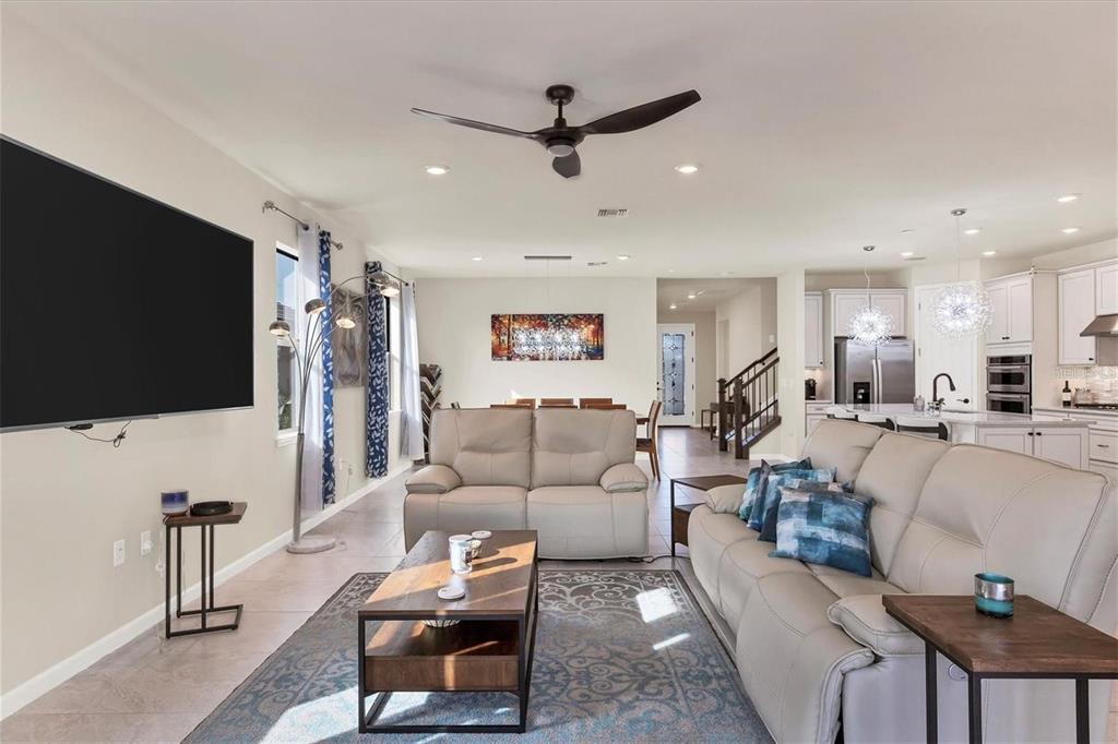 A bright open-concept living room features light tile floors, a ceiling fan, and modern furniture — 5721 SWEET LEAF WAY, SARASOTA, FL