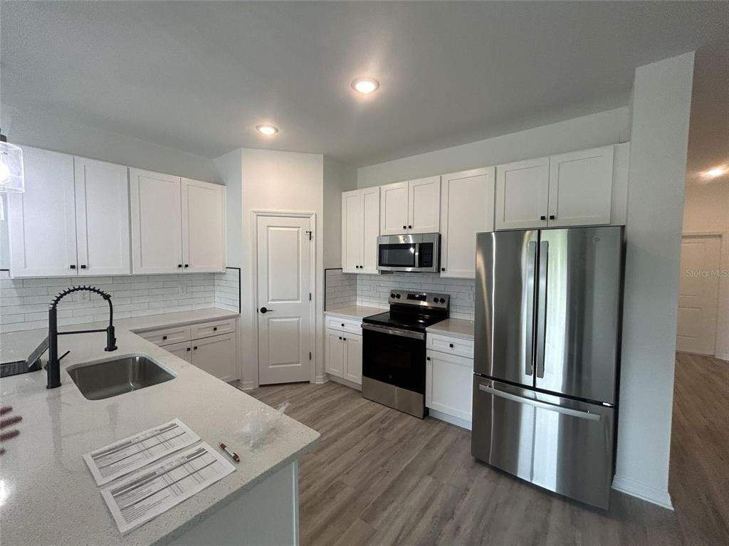 A modern kitchen features white cabinets, stainless steel appliances, and a quartz-topped island — 1320 RIO DE JANEIRO AVENUE, PUNTA GORDA, FL