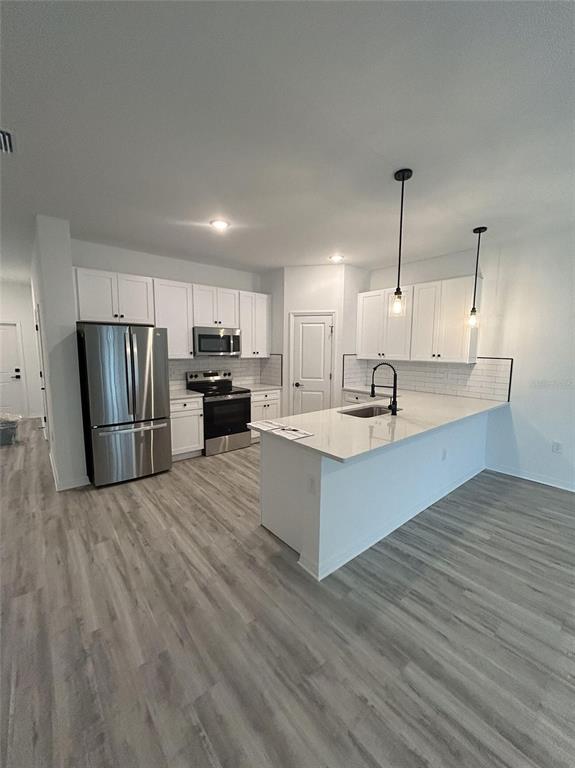 A modern kitchen features white cabinets, stainless steel appliances, and a central island with seating — 1320 RIO DE JANEIRO AVENUE, PUNTA GORDA, FL