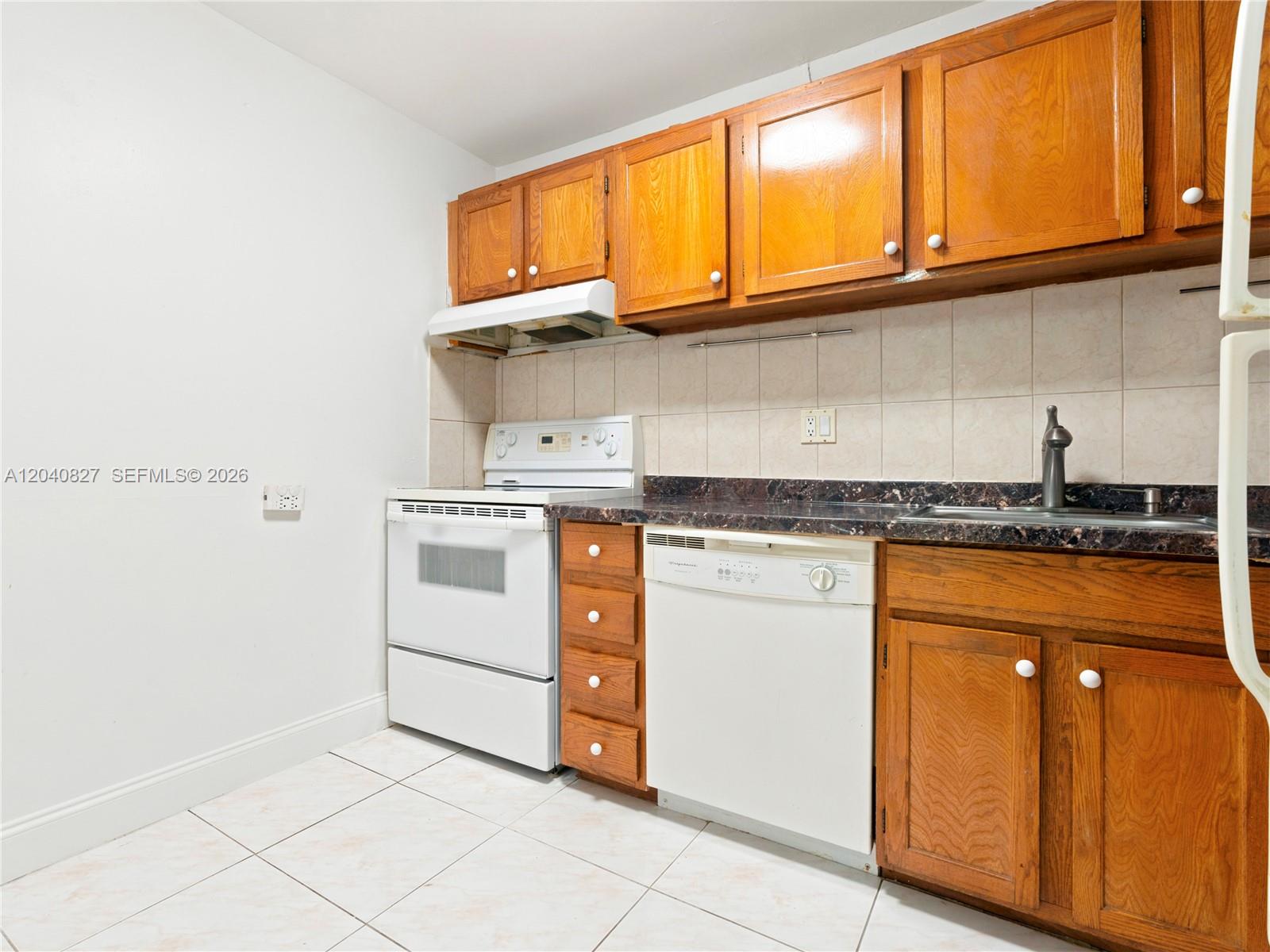 A kitchen features wood cabinets, white appliances, a dark countertop, and light tile flooring — 3740 Inverrary Dr # 3N, Lauderhill FL 33319, LAUDERHILL, FL