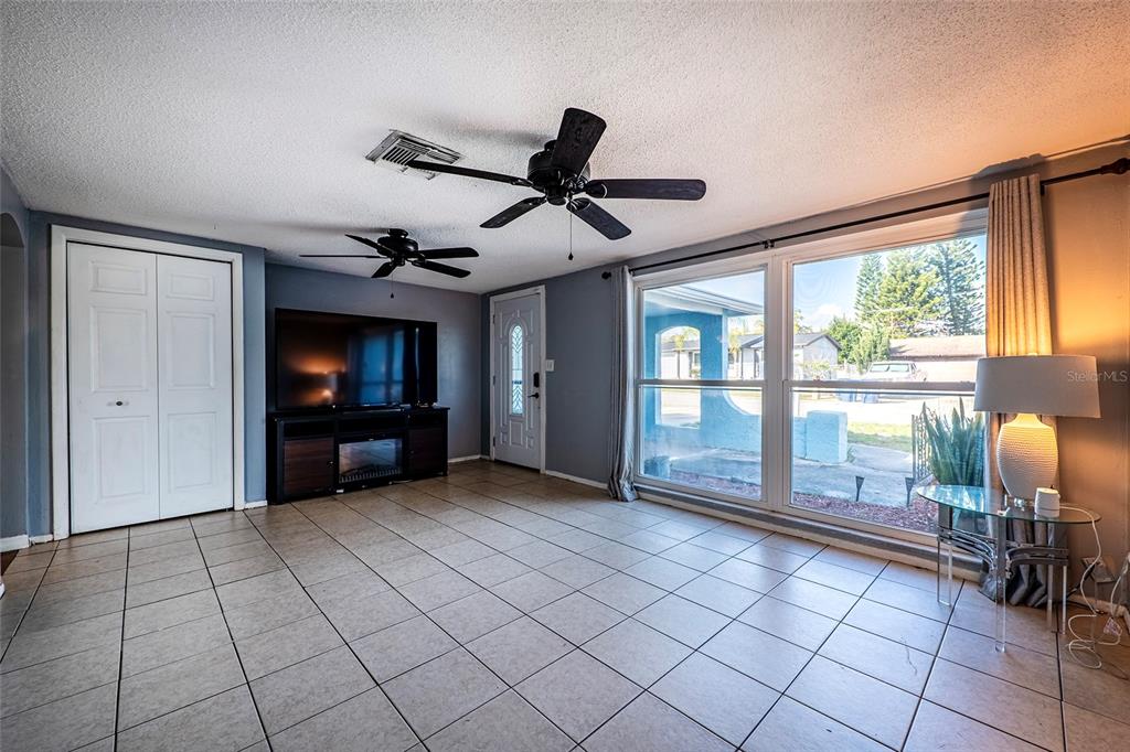 A living room features a large television on a media console and a white door — 9720 GRAY FOX LANE, PORT RICHEY, FL