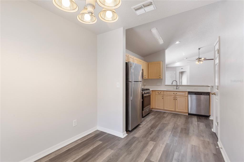 A kitchen with light wood cabinets, stainless steel appliances, and gray wood-look flooring — 7456 OXFORD GARDEN CIRCLE, APOLLO BEACH, FL
