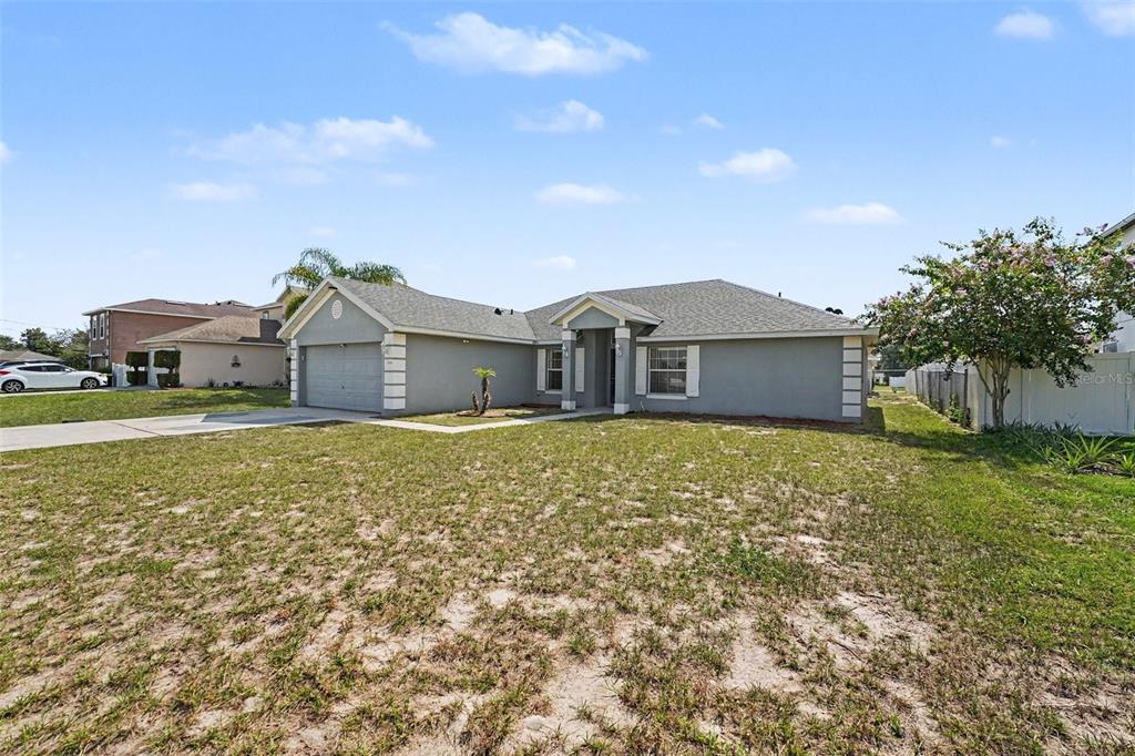 A single-story gray house with a two-car garage and a large front yard — 1714 PILCHARD DRIVE, POINCIANA, FL