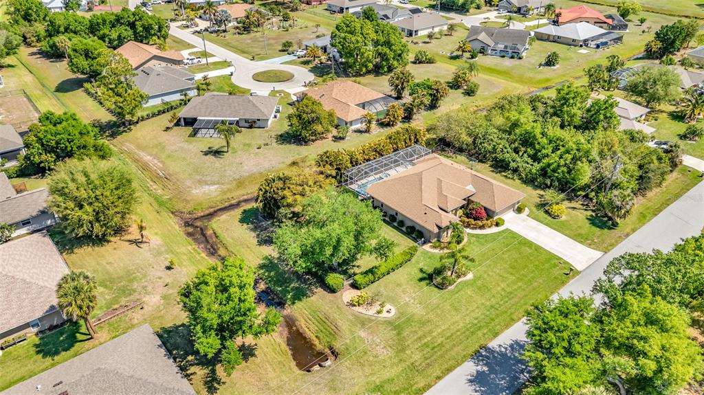 An aerial view shows a suburban neighborhood with single-family homes, green lawns, and trees — 25042 BOLIVAR DRIVE, PUNTA GORDA, FL