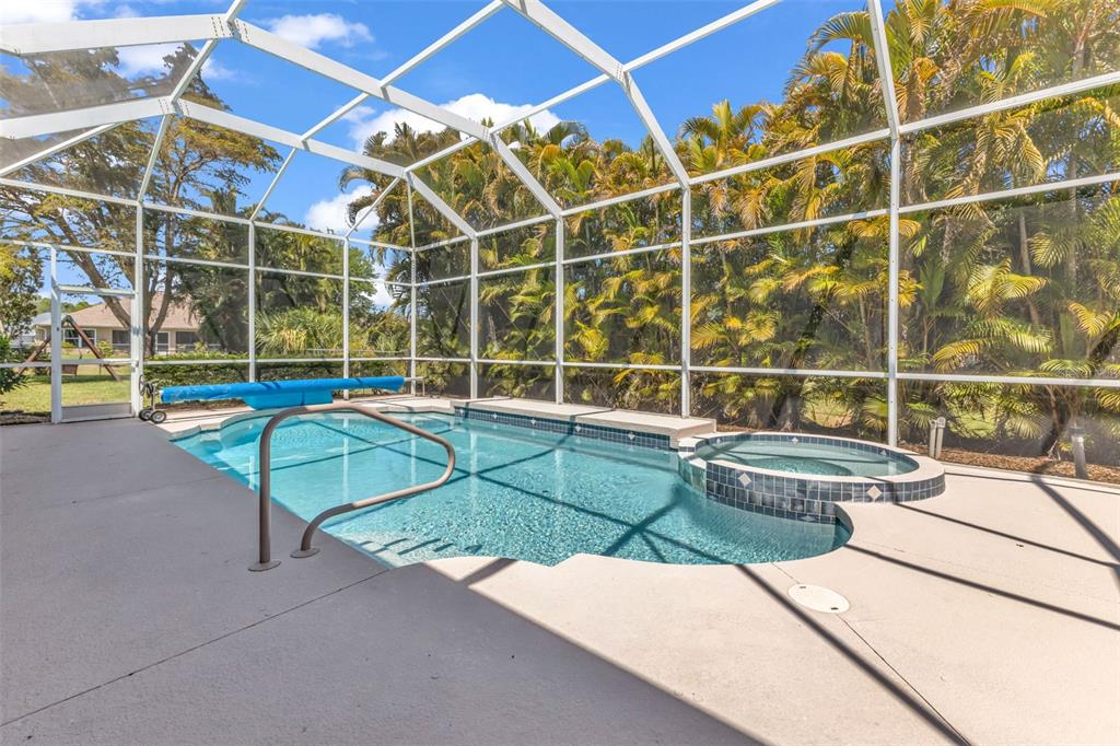A screened-in swimming pool and attached hot tub sit on a concrete patio — 25042 BOLIVAR DRIVE, PUNTA GORDA, FL