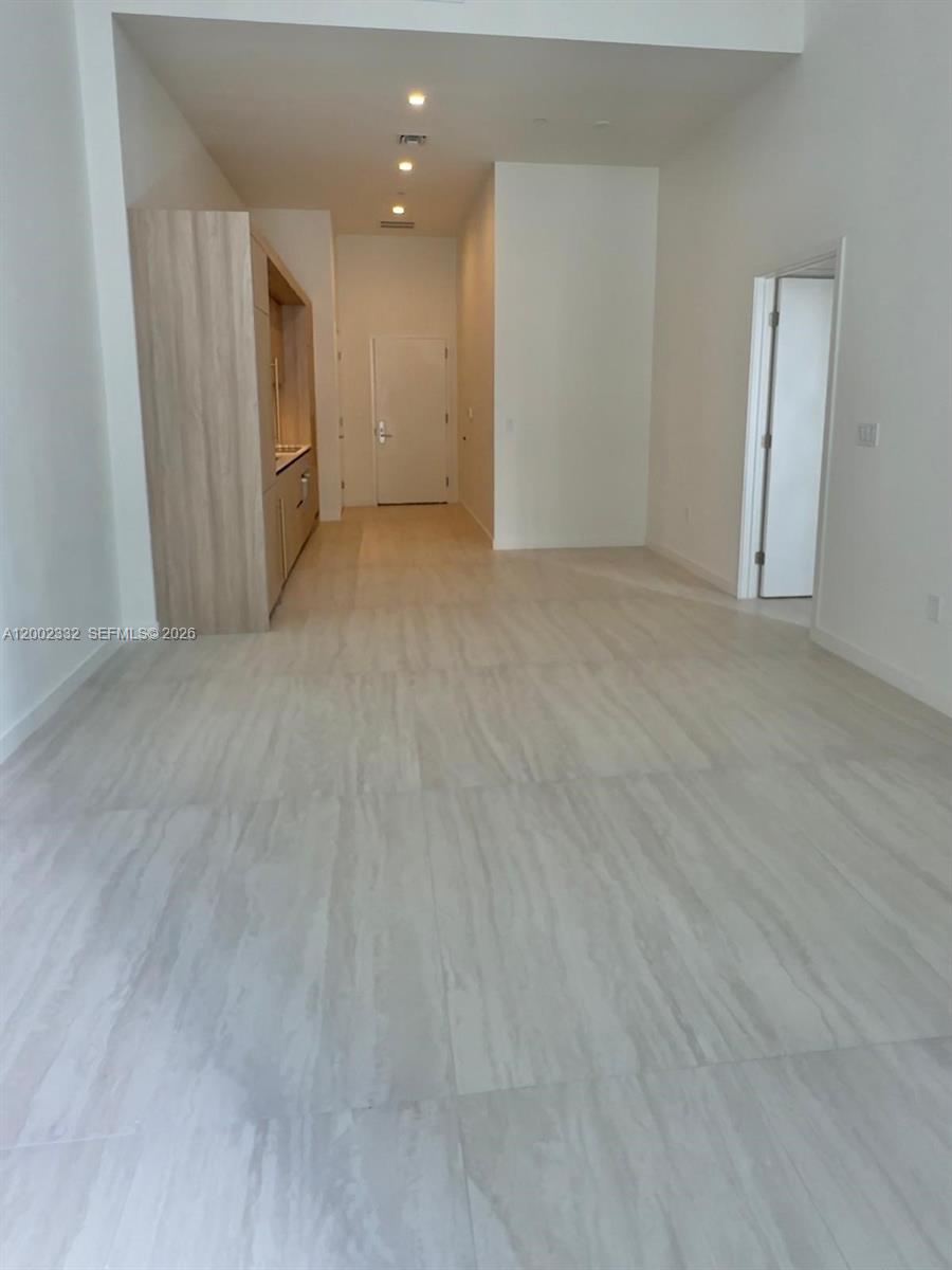 An interior view shows a room with light-colored tile flooring, a kitchenette, and two doorways — 77 SE 5th street # 1010, Miami FL 33131, MIAMI, FL