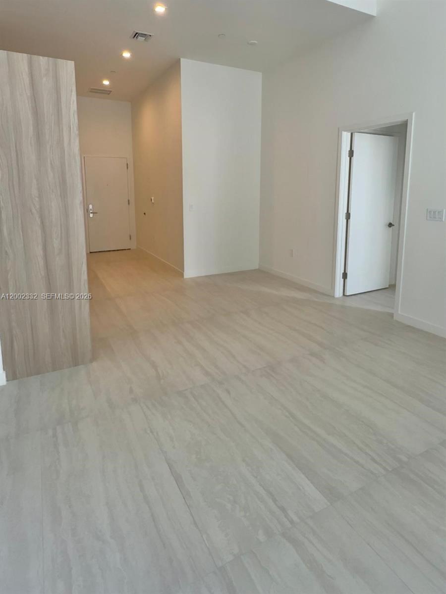 An interior view shows a room with light-colored wood-look flooring and white walls — 77 SE 5th street # 1010, Miami FL 33131, MIAMI, FL