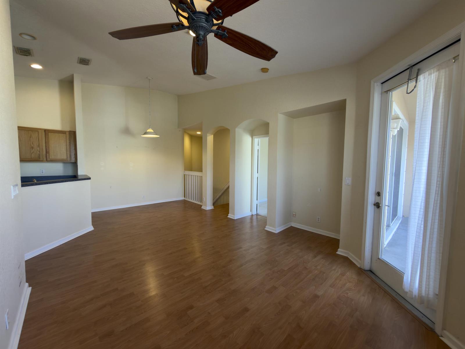 An empty living area features wood-look flooring, a ceiling fan, and a glass patio door — 1712 Carvelle Drive, Riviera Beach FL 33404, RIVIERA BEACH, FL