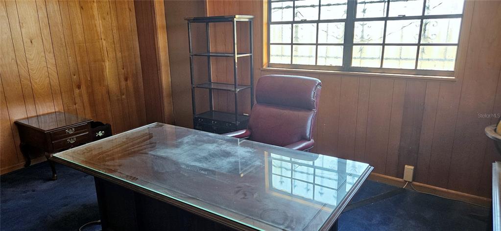 A home office features wood-paneled walls, a glass-topped desk, a leather chair, and blue carpeting — 321 DAVIS BROS ROAD, FROSTPROOF, FL