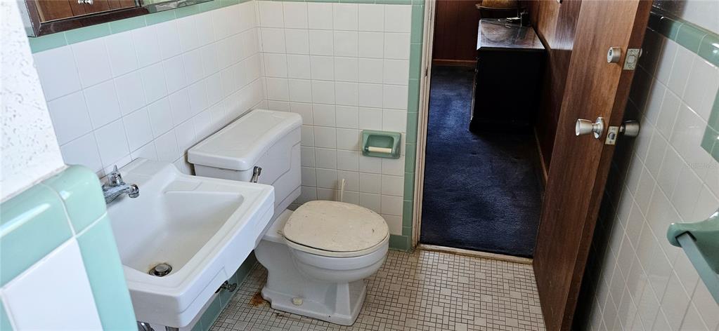 A bathroom features white square wall tiles, green trim, a pedestal sink, and a toilet — 321 DAVIS BROS ROAD, FROSTPROOF, FL