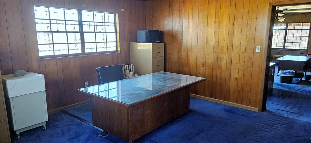 An office with wood-paneled walls, blue carpeting, a glass-topped desk, and a filing cabinet — 321 DAVIS BROS ROAD, FROSTPROOF, FL