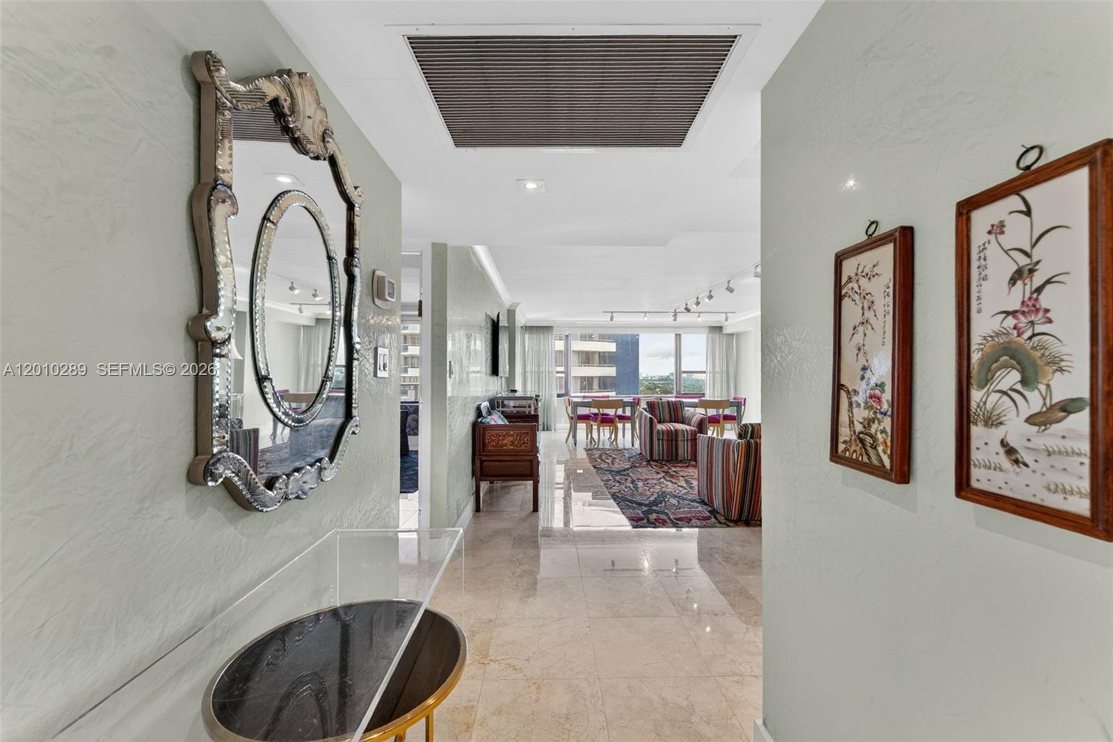 A hallway with a mirror and wall art leads into a living area with tile floors — 5225 Collins Ave # 1519, Miami Beach FL 33140, MIAMI BEACH, FL