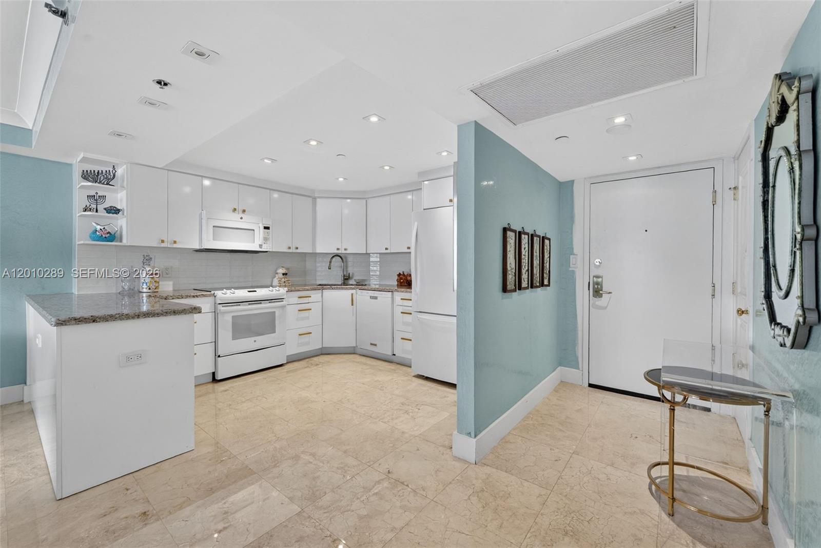 A kitchen with white cabinets, granite countertops, and light tile flooring next to an entryway — 5225 Collins Ave # 1519, Miami Beach FL 33140, MIAMI BEACH, FL