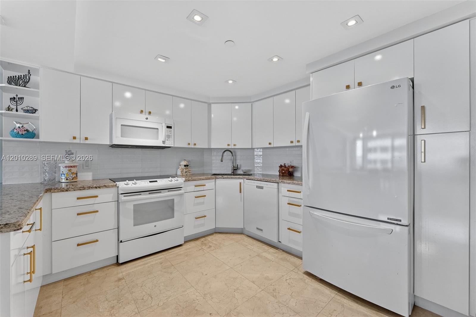 A white kitchen features granite countertops, stainless steel hardware, and tile flooring — 5225 Collins Ave # 1519, Miami Beach FL 33140, MIAMI BEACH, FL