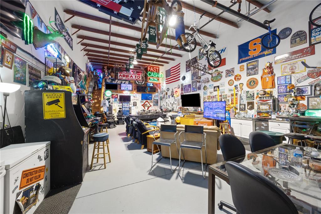 A large, cluttered game room features sports memorabilia, hanging bicycles, arcade cabinets, and lounge seating — 1090 KNIGHTS TRAIL ROAD UNIT 10, NOKOMIS, FL
