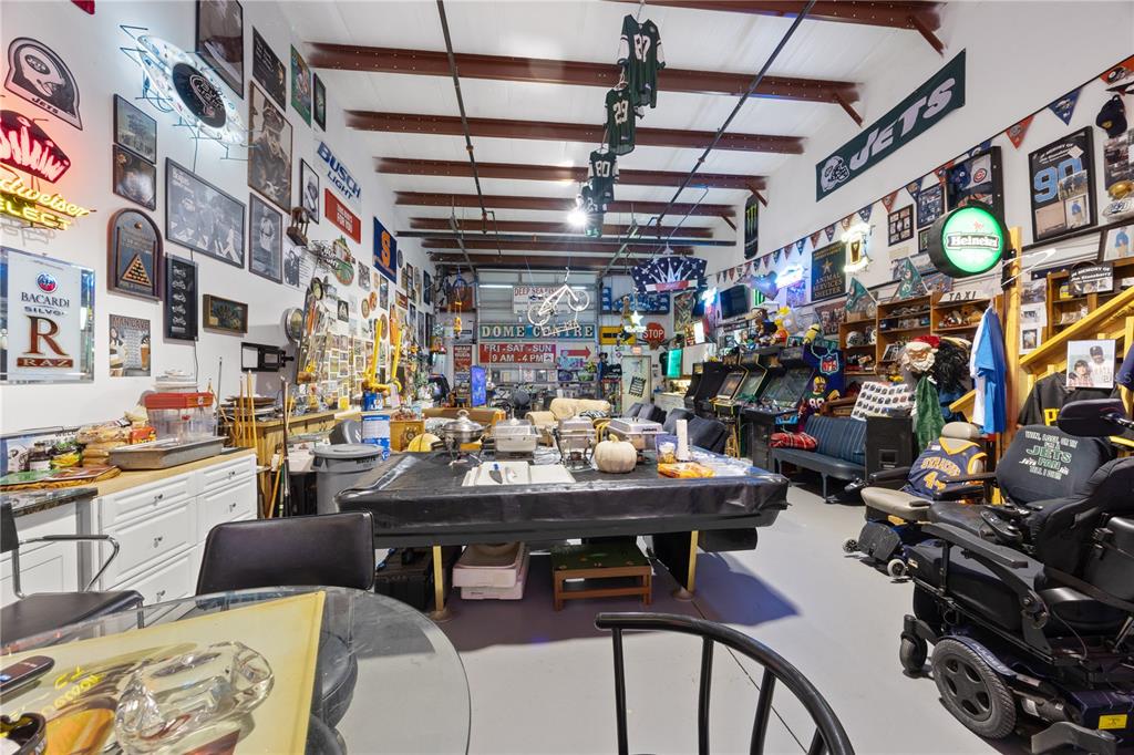 A large, cluttered garage or basement recreation room filled with sports memorabilia and arcade games — 1090 KNIGHTS TRAIL ROAD UNIT 10, NOKOMIS, FL