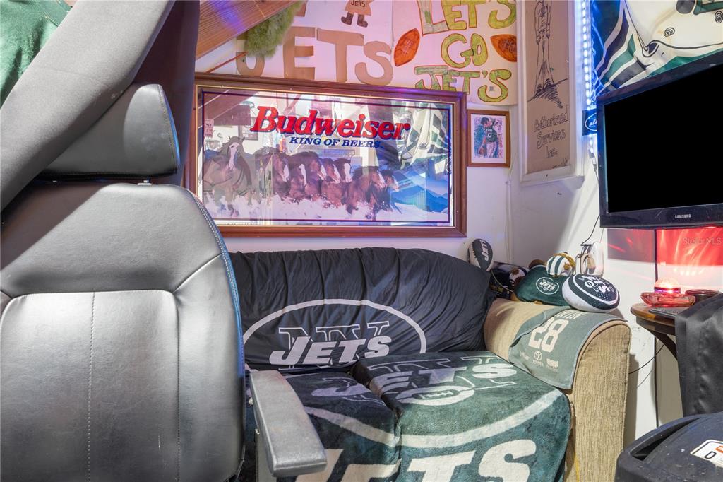 A room decorated with New York Jets memorabilia features a couch, a Budweiser sign, and a television — 1090 KNIGHTS TRAIL ROAD UNIT 10, NOKOMIS, FL