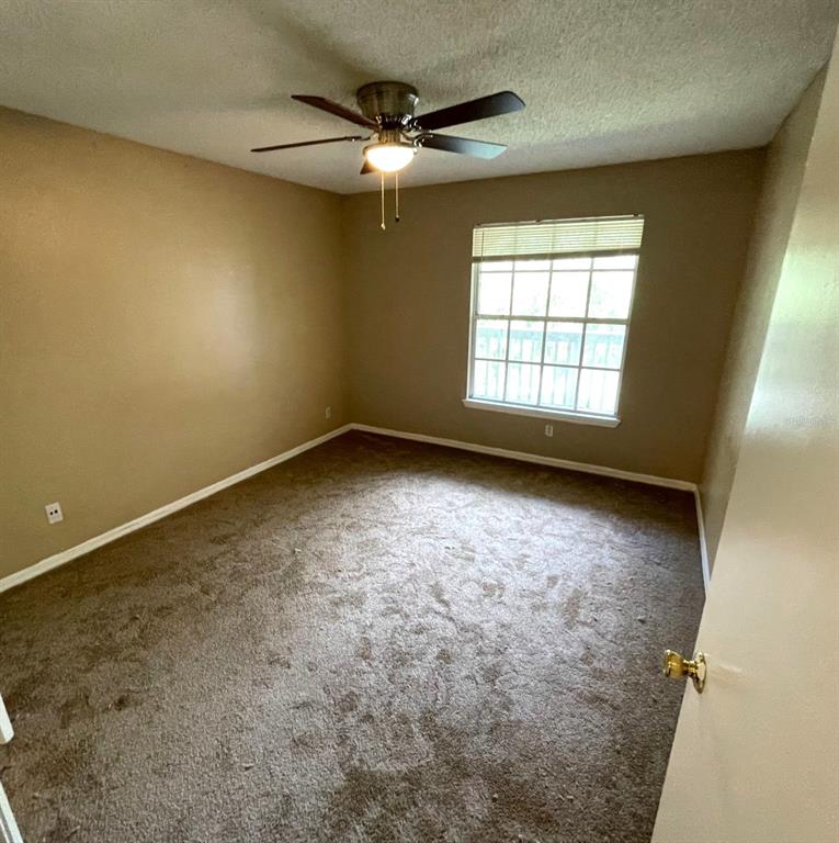 An empty bedroom features tan walls, brown carpet, a ceiling fan, and a single window — 1091 S HIAWASSEE ROAD UNIT 234, ORLANDO, FL