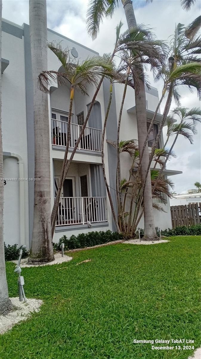 A two-story building exterior features white balconies, gray trim, and several tall palm trees — 9248 Collins Ave # 205, Surfside FL 33154, SURFSIDE, FL