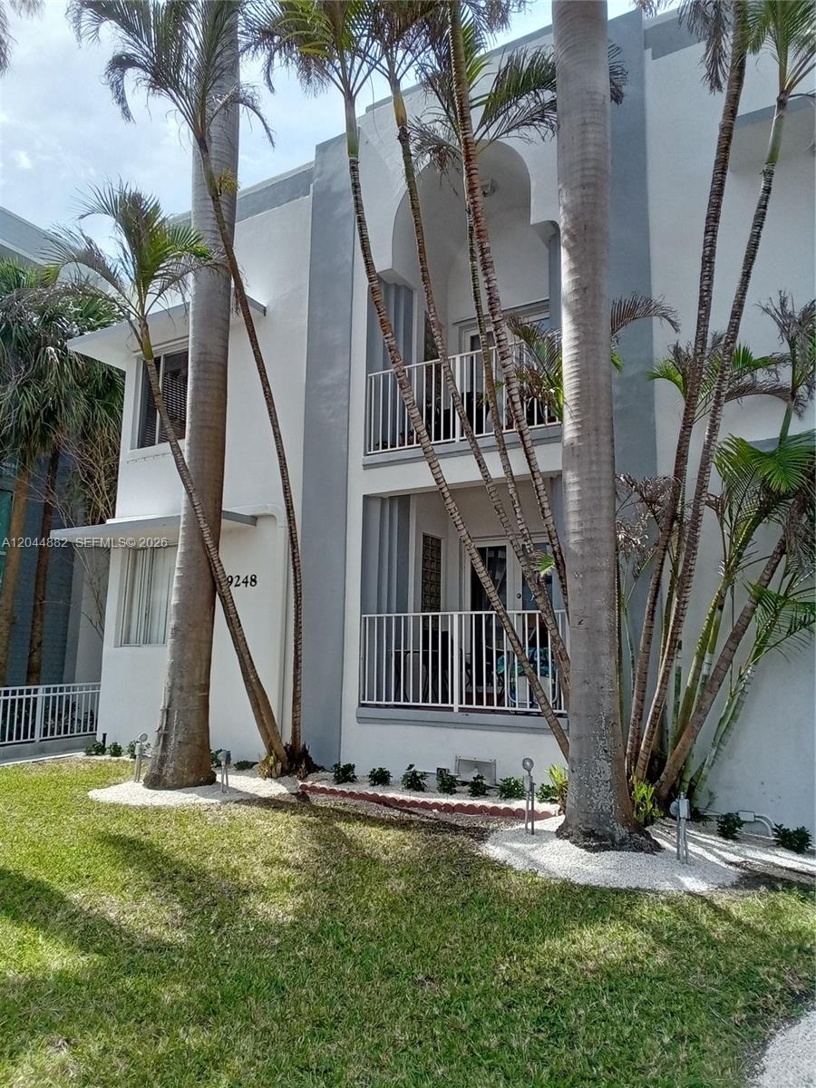A two-story white building features balconies, gray accents, and several tall palm trees — 9248 Collins Ave # 205, Surfside FL 33154, SURFSIDE, FL