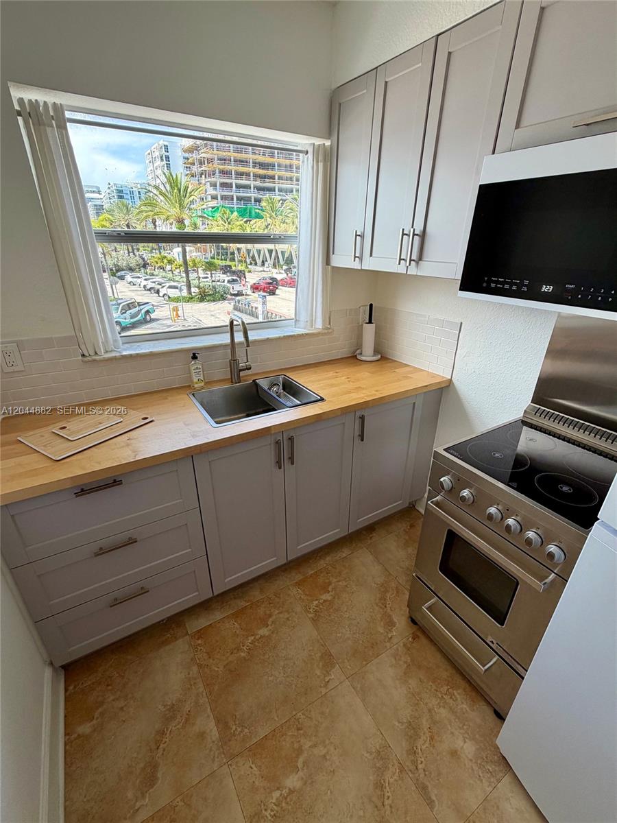 A kitchen features light gray cabinets, a wood countertop, and a window overlooking a street — 9248 Collins Ave # 205, Surfside FL 33154, SURFSIDE, FL