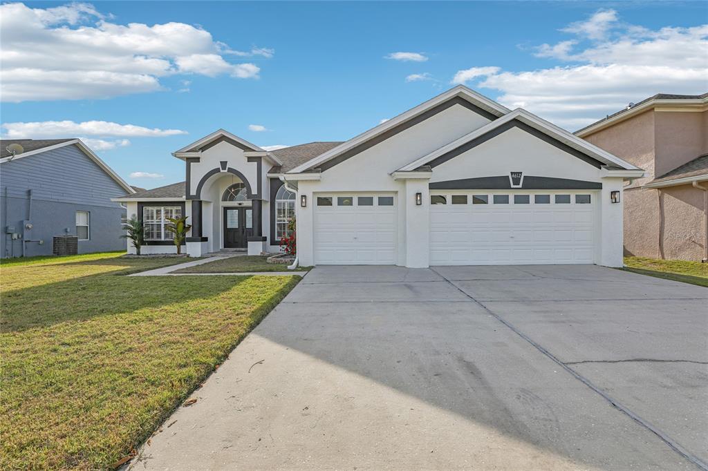 A single-story house features a white stucco exterior, a two-car garage, and an arched entryway — 4612 HURON BAY CIRCLE, KISSIMMEE, FL