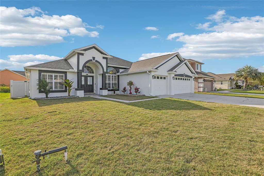 A single-story white house with a dark trim, arched entryway, and a three-car garage — 4612 HURON BAY CIRCLE, KISSIMMEE, FL