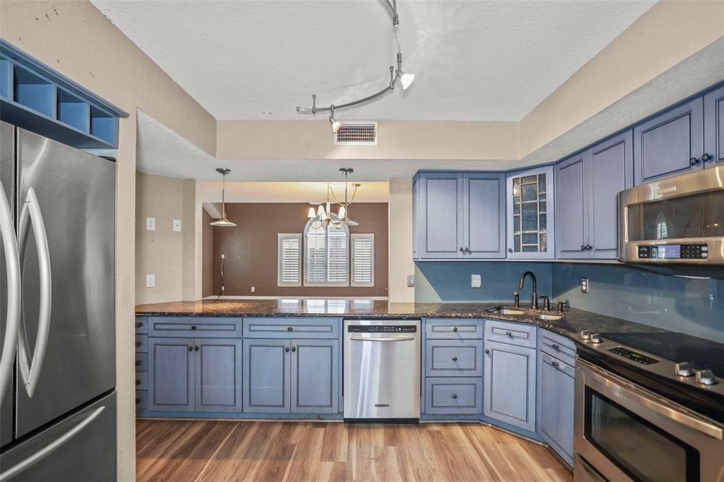 A kitchen with blue cabinets, stainless steel appliances, and dark granite countertops — 1668 HAMILTON COURT UNIT 2061, DUNEDIN, FL