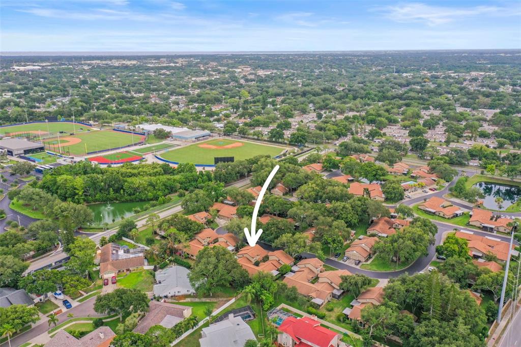 An aerial view shows a residential neighborhood with a white arrow pointing to a townhouse — 1668 HAMILTON COURT UNIT 2061, DUNEDIN, FL