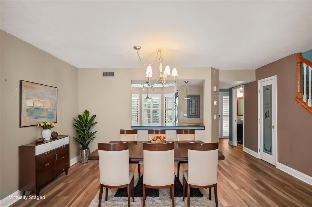A dining room features a wooden table, six chairs, a sideboard, and light wood flooring — 1668 HAMILTON COURT UNIT 2061, DUNEDIN, FL
