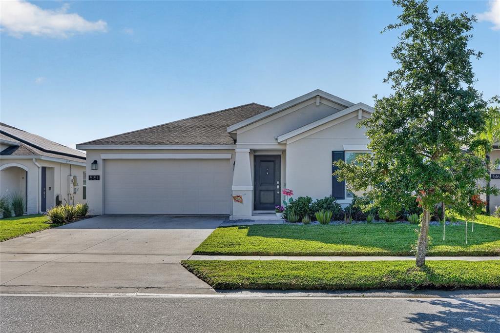 A single-story house with a beige stucco exterior, a two-car garage, and a front lawn — 5151 FOUR STRAND COURT, ST CLOUD, FL
