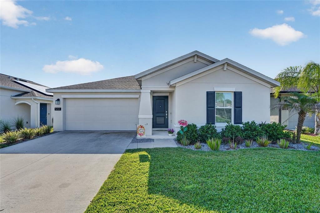 A single-story suburban house with a beige stucco exterior, a two-car garage, and a lawn — 5151 FOUR STRAND COURT, ST CLOUD, FL