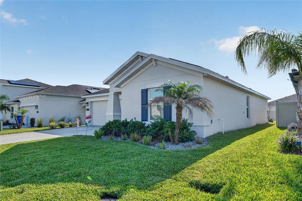 A single-story house with a beige stucco exterior, blue shutters, and a front lawn — 5151 FOUR STRAND COURT, ST CLOUD, FL
