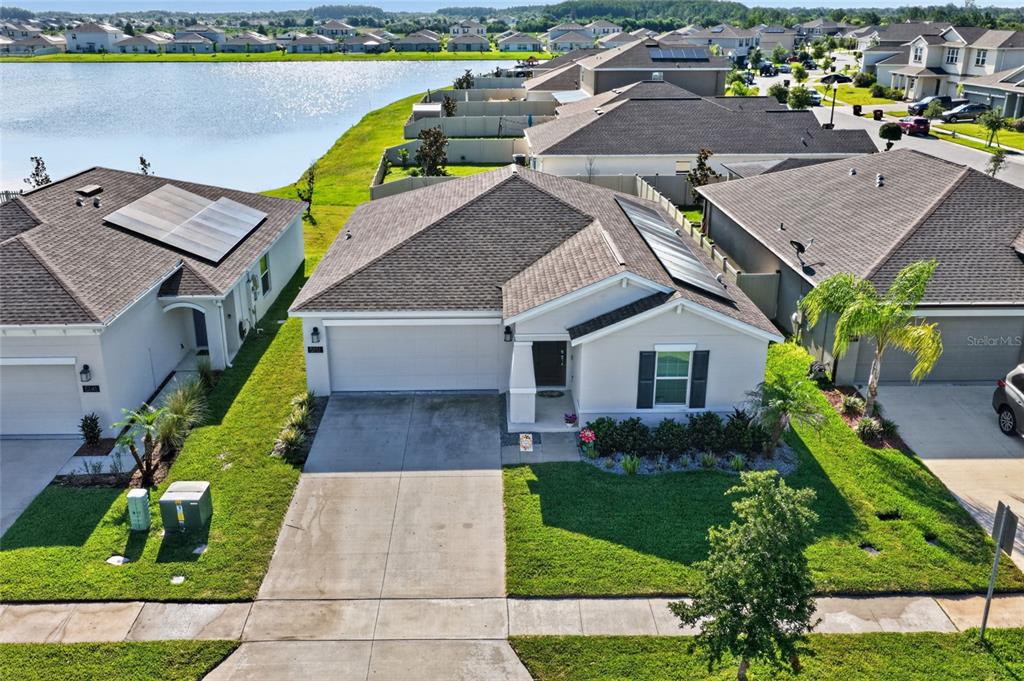 An aerial view shows a suburban house with a solar-paneled roof near a lake — 5151 FOUR STRAND COURT, ST CLOUD, FL