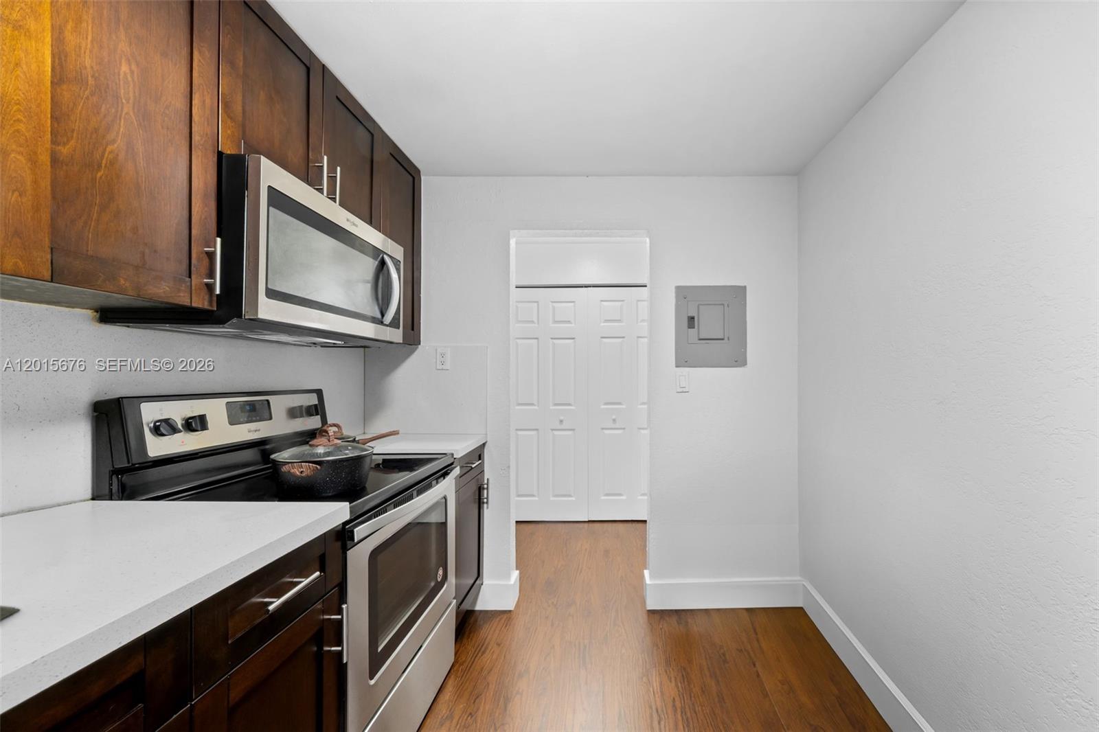 A kitchen features dark wood cabinets, stainless steel appliances, white countertops, and wood-look flooring — 1800 Sans Souci # 332, North Miami FL 33181, NORTH MIAMI, FL