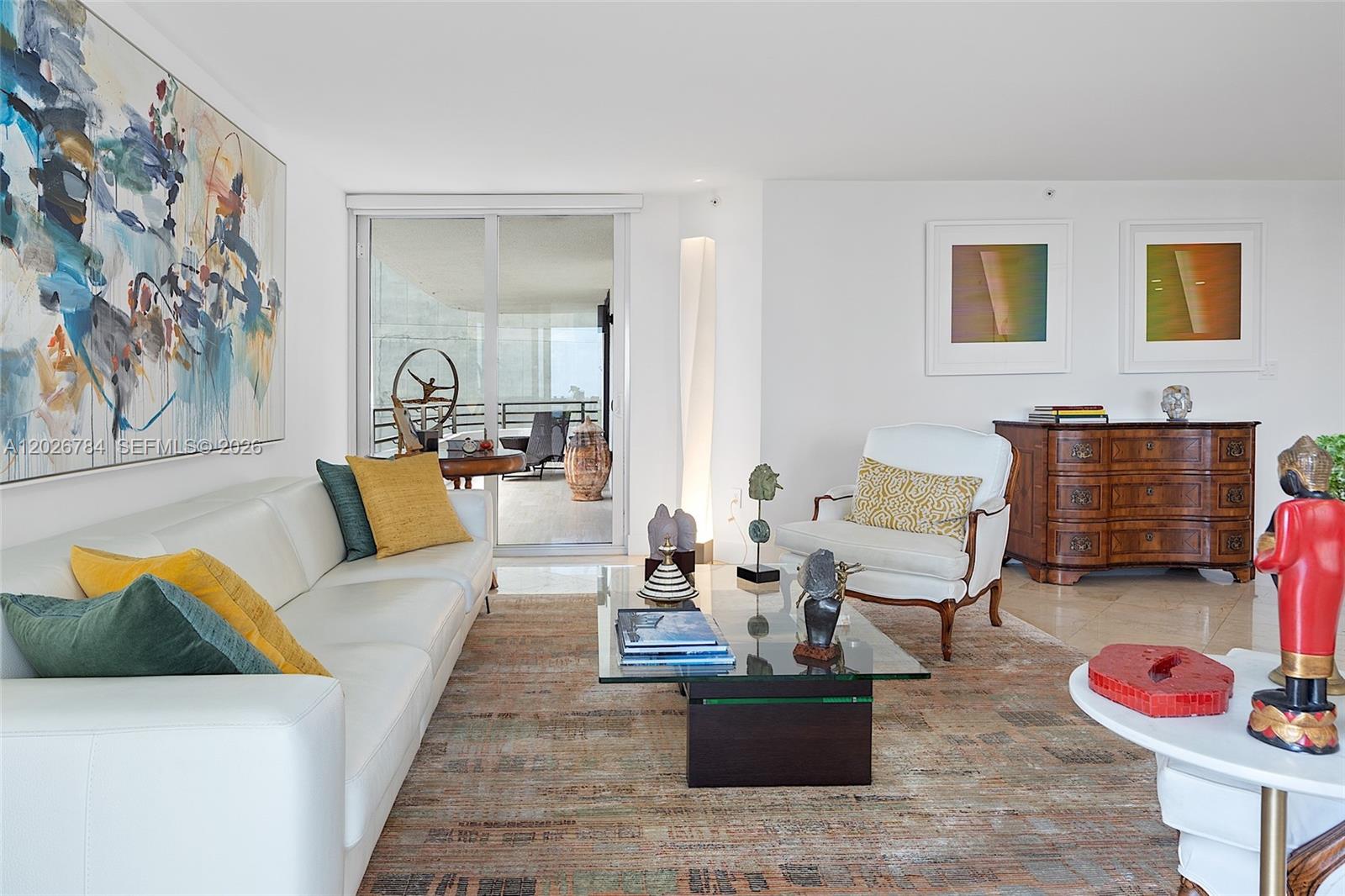 A living room features a white sofa, glass coffee table, and a balcony with views — 151 SE 15th Rd # 601, Miami FL 33129, MIAMI, FL
