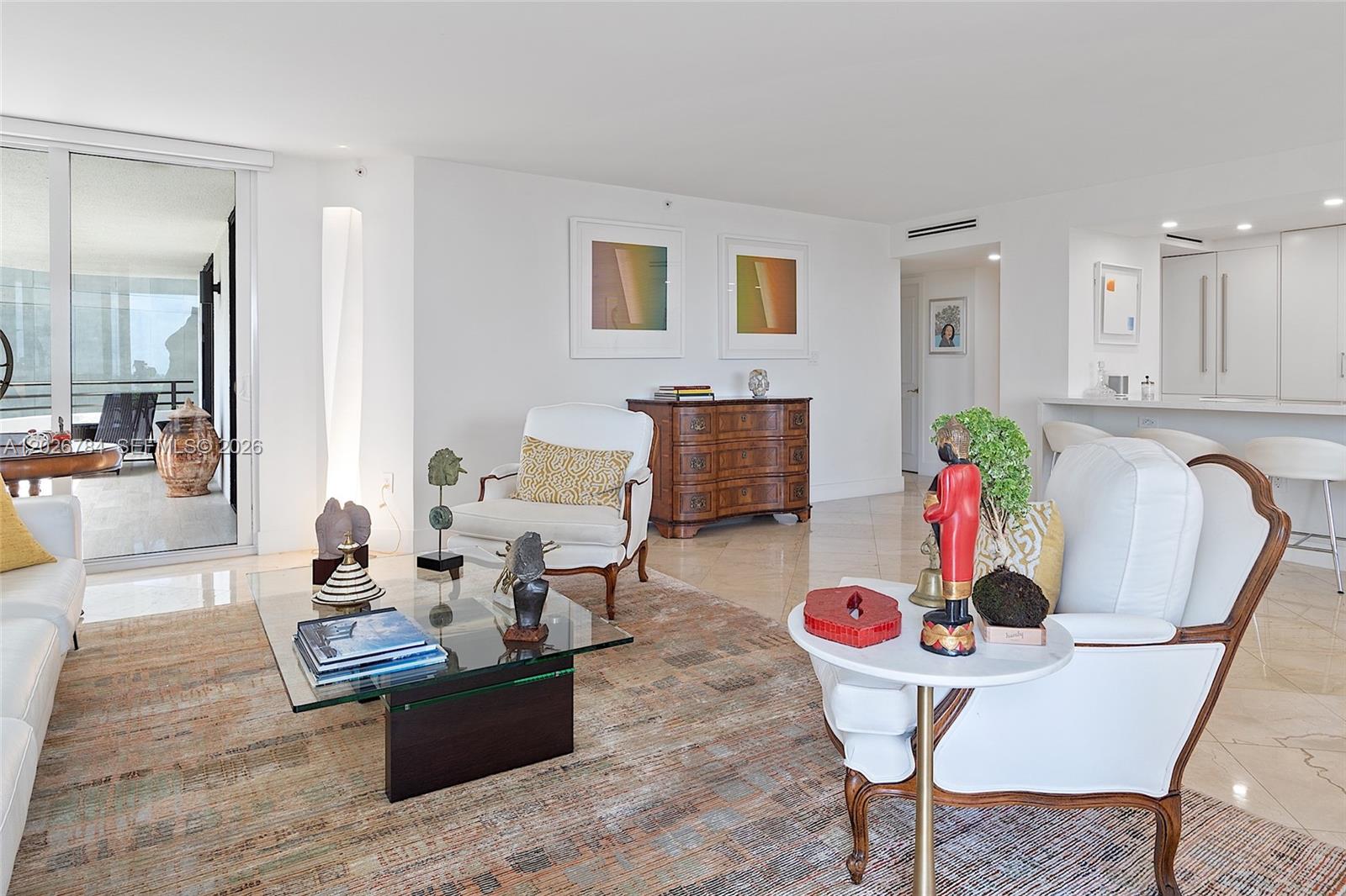 A bright living room features white furniture, a glass coffee table, and a balcony view — 151 SE 15th Rd # 601, Miami FL 33129, MIAMI, FL
