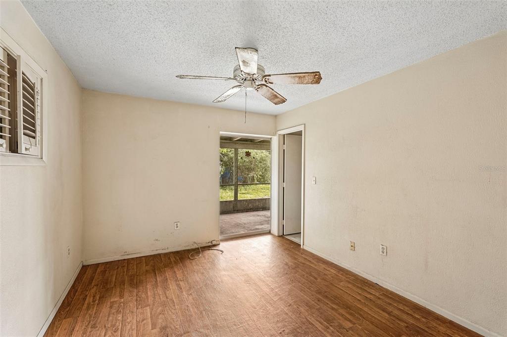 An empty room with wood-look flooring, a ceiling fan, and a sliding door to a porch — 838 CORDELE AVENUE NW, PORT CHARLOTTE, FL