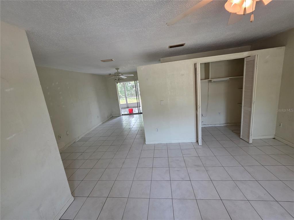 An open-concept living area features white tile flooring, a closet, and a sliding glass door — 838 CORDELE AVENUE NW, PORT CHARLOTTE, FL