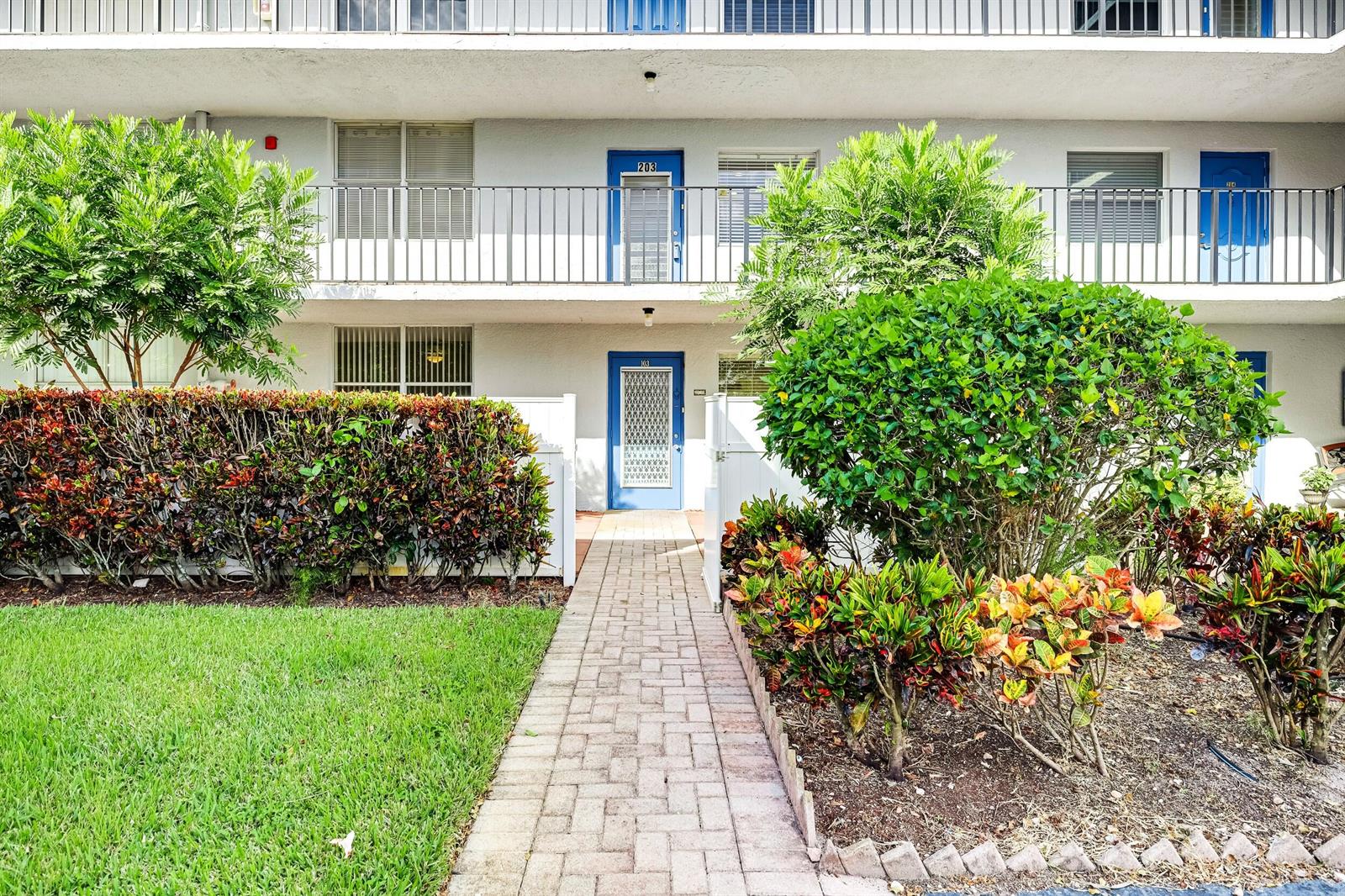 A paved walkway leads to the blue front door of a two-story apartment building — 6650 S Oriole Boulevard # 1030, Delray Beach FL 33446, DELRAY BEACH, FL